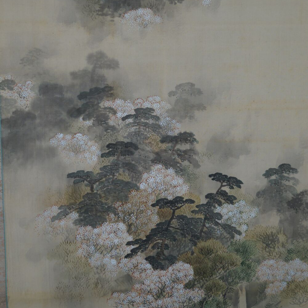 Primo piano degli alberi in fiore e dei pini nella parte superiore dell'immagine del kakemono fiume nella valle in fiore