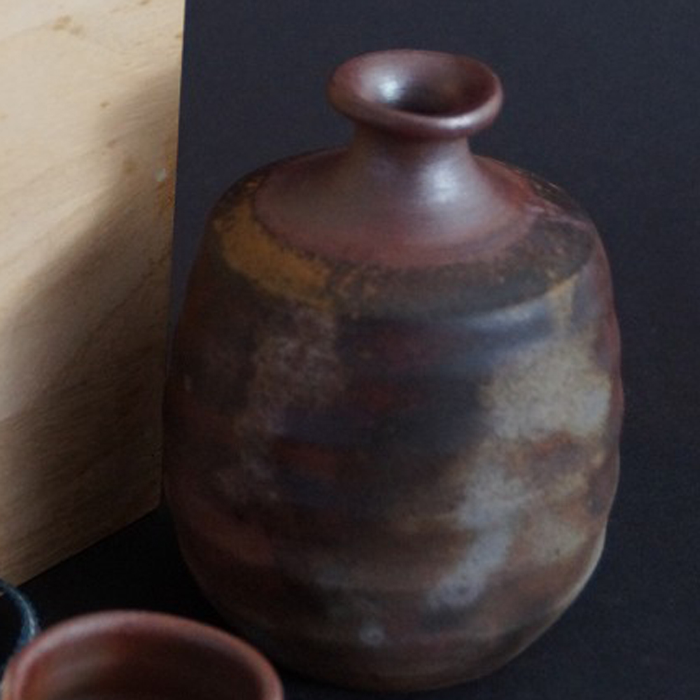 Apercu gros plan du flacon a sake en céramique de Bizen avec la boîte de conservation en arriere-plan