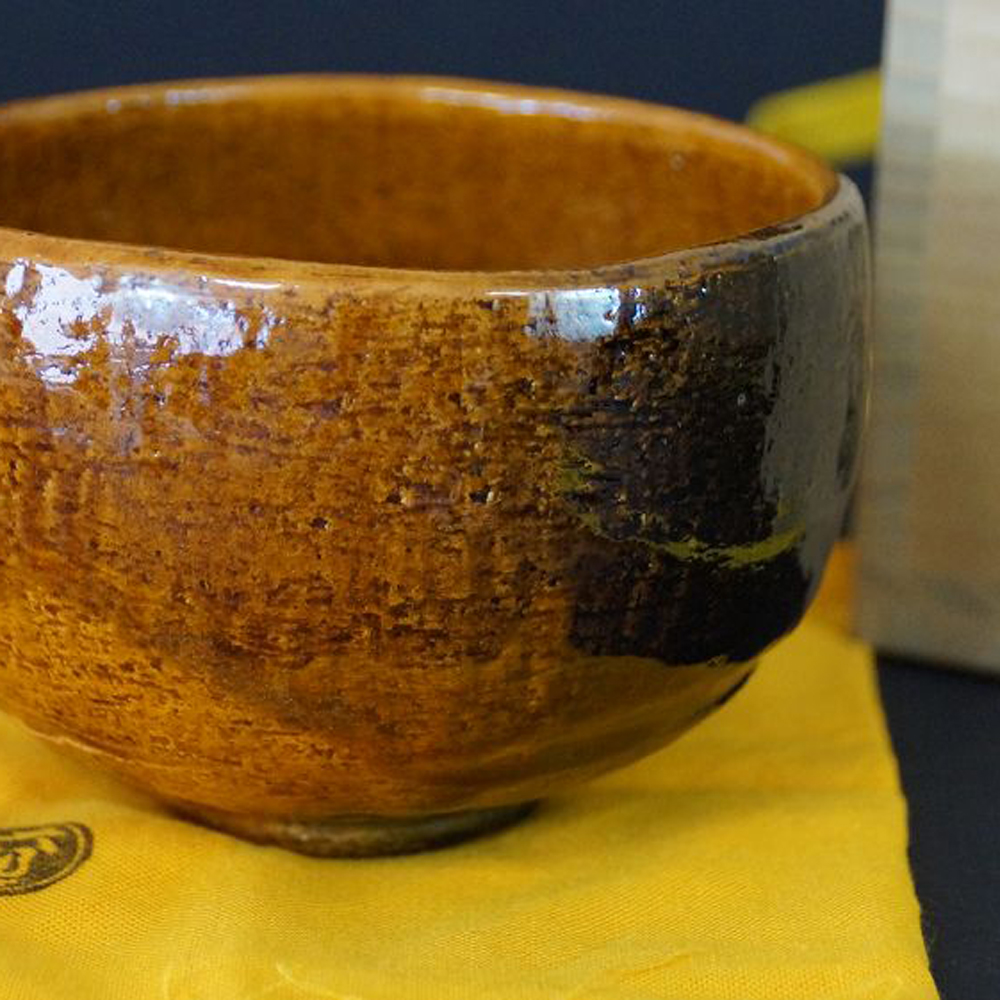 Czarka do herbaty chawan z ceramiki z Ohi autorstwa Hisashi Ohi w widoku całości z pomarańczowo-brązowym szkliwem