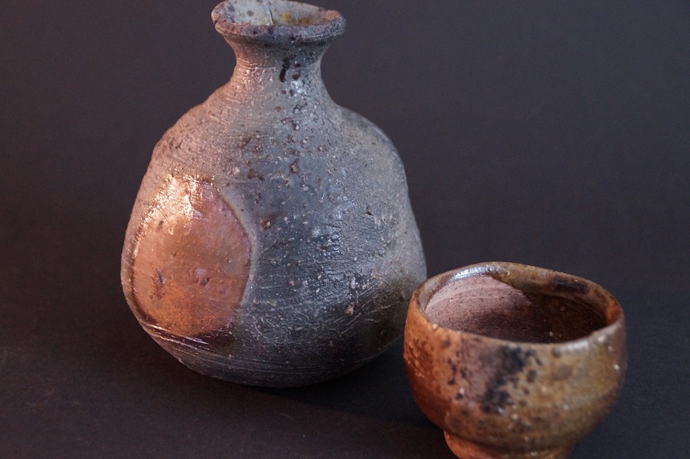 Vue de face du service à saké non émaillé en céramique de Bizen composé d'un tokkuri et de guinomi