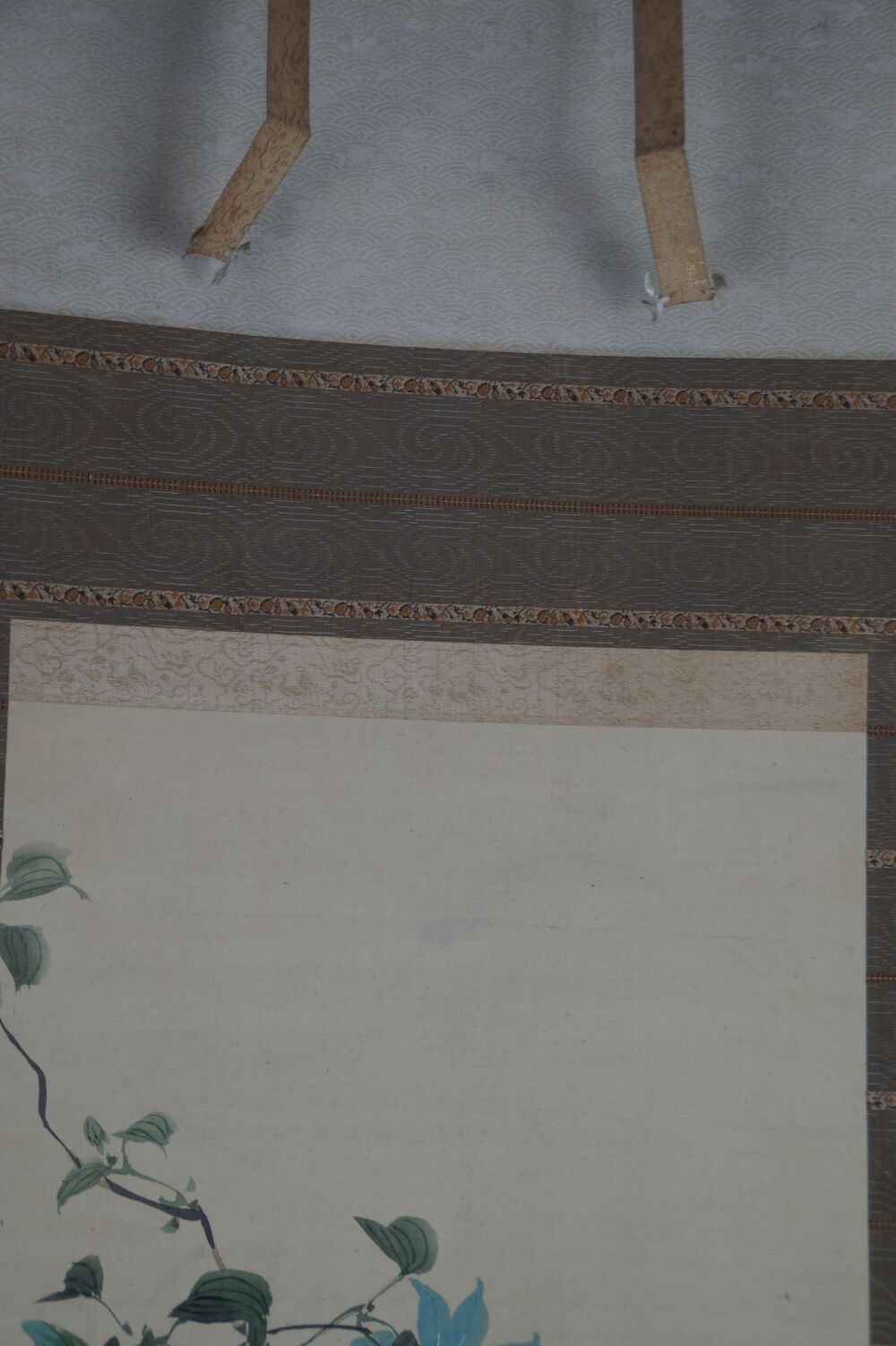 Detailansicht der Seidenmontierung mit Wellenmuster und Aufhaengebaendern des Kakemono