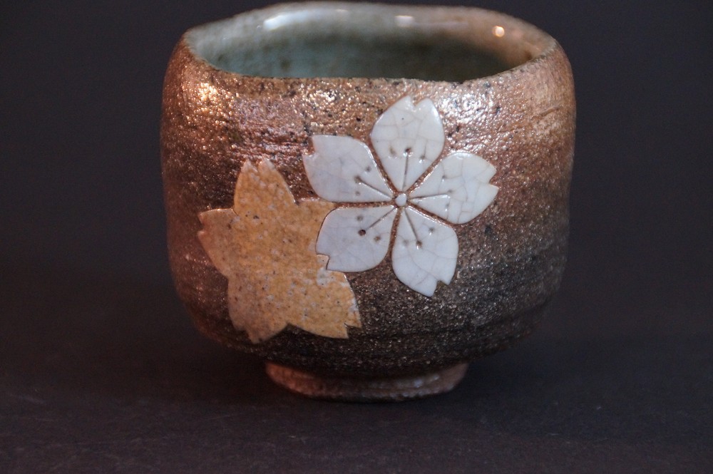 Vue de face de la coupelle a sake Karatsu tournée à la main avec motif de fleurs de cerisier