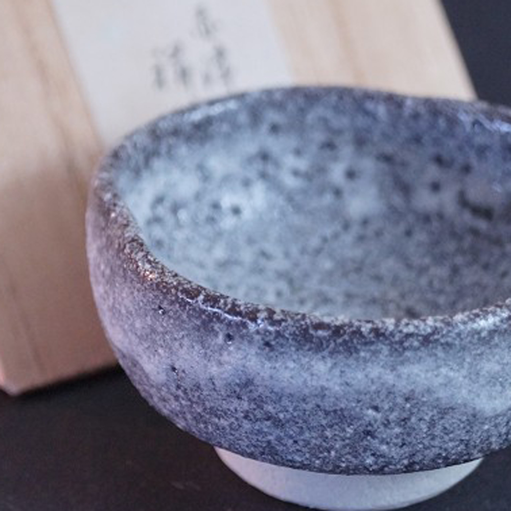 Aperçu en gros plan de la coupe à saké en céramique Shino avec boîte de conservation à l'arrière-plan